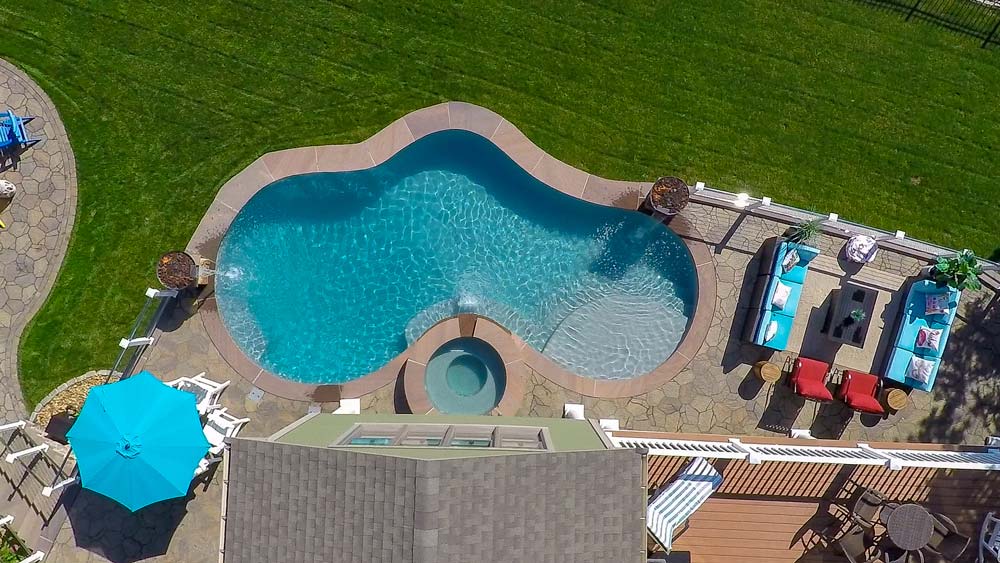 Aerial view of pool in backyard with fire pit and yard kitchen