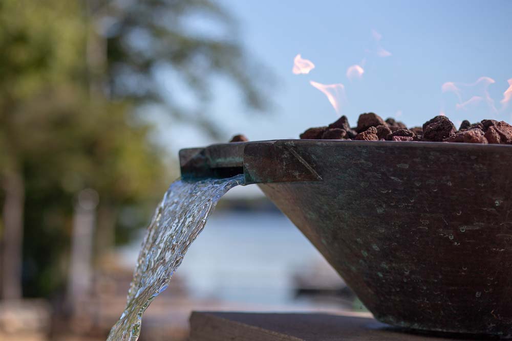 Decorative water streams with fire next to pool