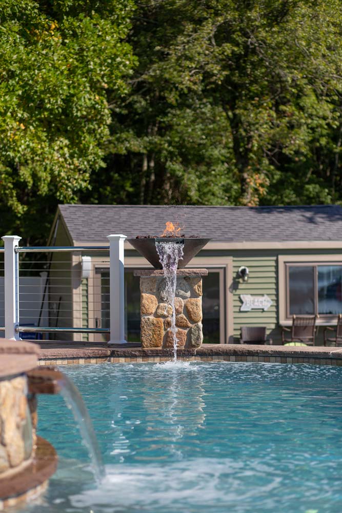 Decorative water streams with fire next to pool