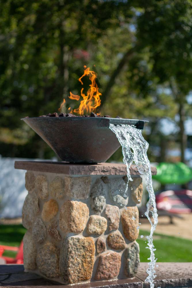 Decorative water streams with fire next to pool